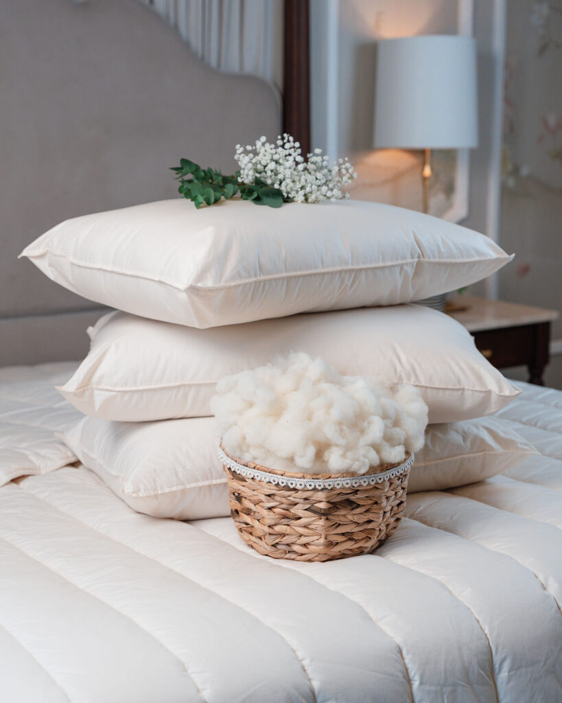 A set of wool pillows from dooley's wool on a neat bed with raw wool in front of it. Real wool pillows Ireland.
