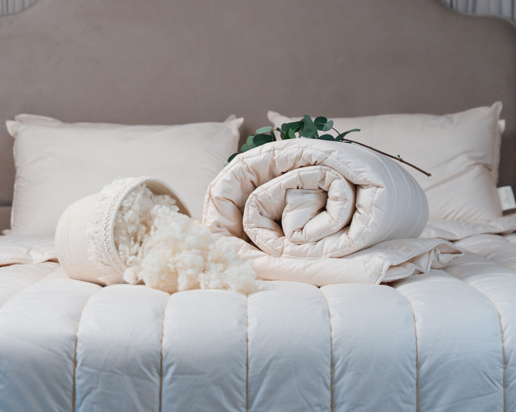 A duvet on a neatly made bed with dooley's wool products and raw wool besides it. Real wool duvet Ireland.